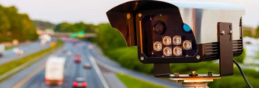 A pole-mounted plate-recognition camera above a road